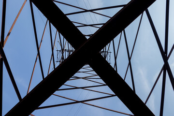 Detail of an electricity pylon against blue sky: high voltage electric cables seen from below