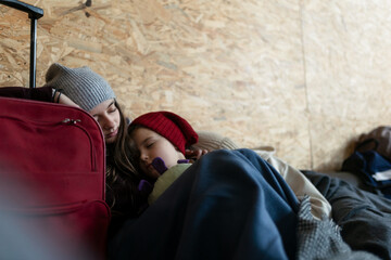 Ukrainian war refugees in temporary shelter and help center, children tired and sleeping.