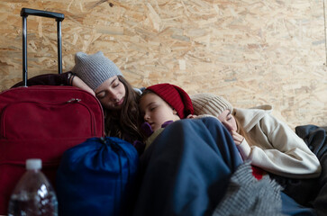 Ukrainian war refugees in temporary shelter and help center, children tired and sleeping.