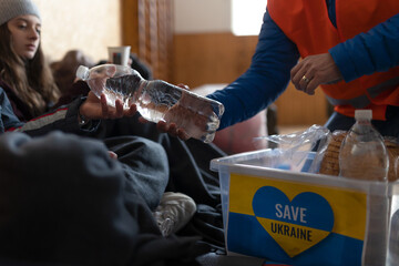 Ukrainian war refugees in temporary shelter and help center getting drinks from volunteers.