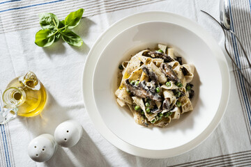 plate with tagliatelle pasta, mushrooms and green peas on the table