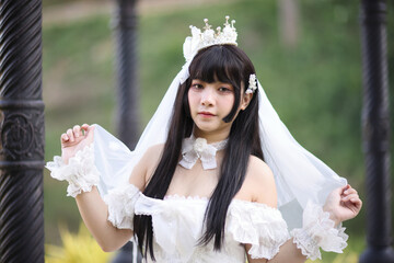 Beautiful young woman with white lolita dress with european garden Japanese fashion