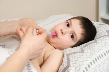 A mother or doctor gives a 4-year-old child a medicine for fever or cough. Treatment of children...