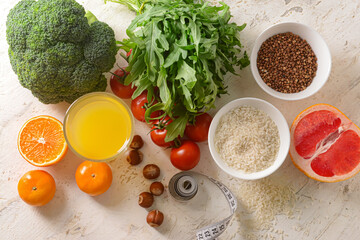 Composition with healthy products, glass of juice and measuring tape on light background
