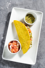 corn tacos with salmon, mayonnaise and pistachios on a concrete table