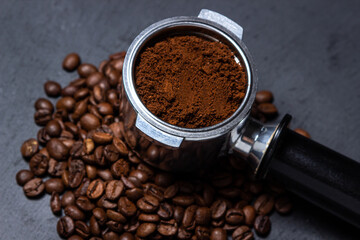 Ground coffee and coffee beans on a black background. Preparing coffee in a coffee machine.