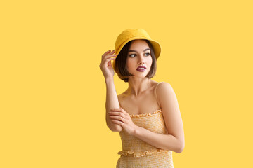 Young woman with dark lipstick in bucket hat on color background © Pixel-Shot