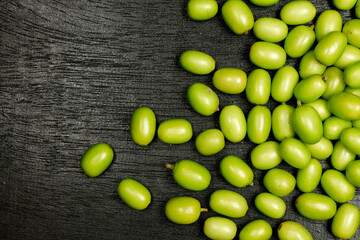 Fresh Neem fruit on black wooden background. Neem fruit is an excellent moisturizing and contains various compounds that have insecticidal and medicinal properties.