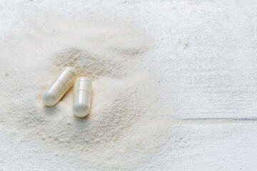 collagen in tablets and powder on wooden white background.