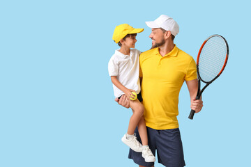 Little boy and his trainer with tennis racket on blue background