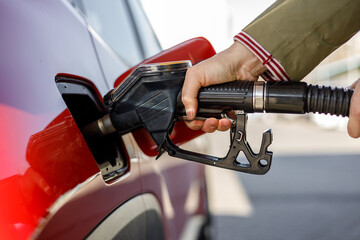 Hand fulfill fuel gasoline dispenser in station - obrazy, fototapety, plakaty