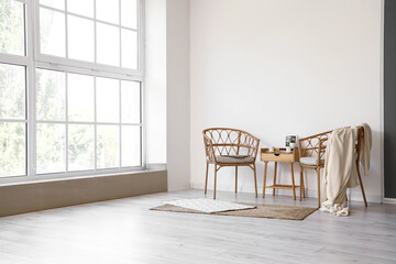 Stylish interior with bedside table and wicker chairs near window