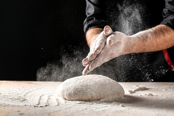 White flour flying into air as pastry chef in white suit slams ball dough on white powder covered table. concept of nature, Italy, food, diet and bio.