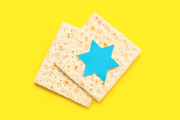 Jewish flatbread matza for Passover with paper David star on yellow background