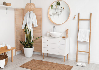 Interior of light bathroom with sink, mirror and wooden folding screen
