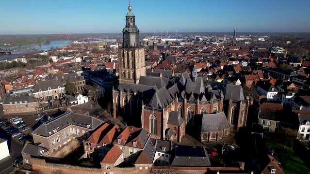 Aerial descend and reveal of medieval city wall and authentic historic rooftops and rising Walburgis church in Hanseatic tower town Zutphen. Europe history picturesque painterly aerial cityscape.