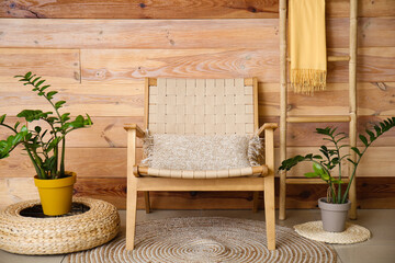 Fototapeta na wymiar Stylish armchair, houseplants and ladder near wooden wall