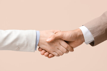 Business colleagues shaking hands on beige background, closeup