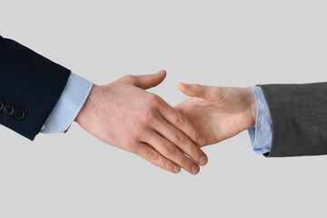 Business workers shaking hands on light background, closeup