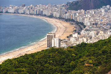 Obraz premium Aerial view of Copacabana beach with its buildings, sea and landscape. Huge hills along the entire length. Immensity of the city of Rio de Janeiro, Brazil in the background