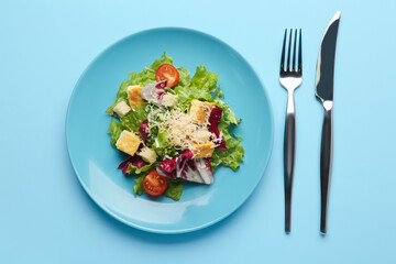 Plate with tasty vegan Caesar salad on blue background