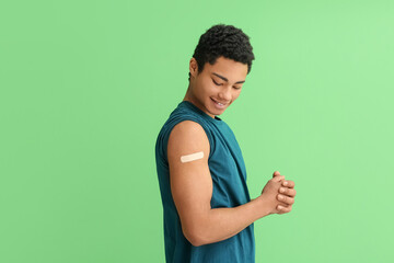 Young African-American man with applied medical patch on green background