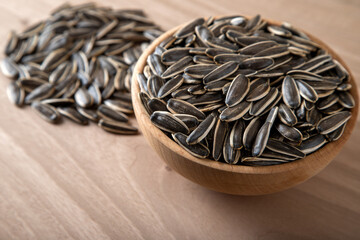 Black sunflower seeds in a bowl on wooden background	