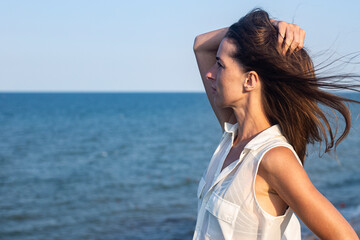 Beautiful sexy young woman in a light pareo on a cliff looks at the sea.