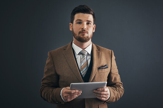 Determined To Make It Happen No Matter What. Studio Portrait Of A Handsome Young Businessman Using A Digital Tablet Against A Dark Background.