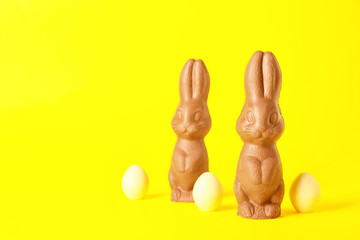 Chocolate Easter bunnies and eggs on yellow background