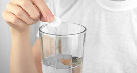 A woman's hand puts a soluble pill into a glass