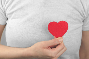 A woman holds a red heart in her hand in front of her. Valentine's Day. World Heart Day.