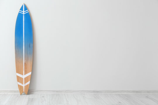 Wooden surfboard near light wall