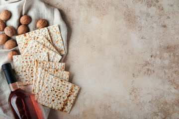 Passover celebration concept. Matzah, red kosher and walnut. Traditional ritual Jewish bread on sand color old concrete background. Passover food. Pesach Jewish holiday.