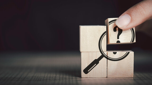  Hand Hold Magnifying Glass And Question Mark Sign Icon In Wooden Cube. Problems And Root Cause Analysis Concept. Copy Space For Background Or Text.