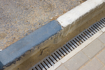 square curbstone and drainage grate by the road