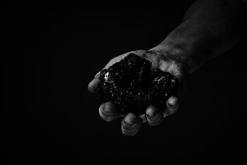 Dirty hands miner holding coal in black and white photo.Heavy coal mining.