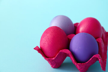 Holder with painted Easter eggs on color background, closeup