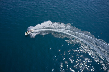 Top view. Boat in turn fast moving aerial view. One boat on blue water drone view. Modern boat in a...