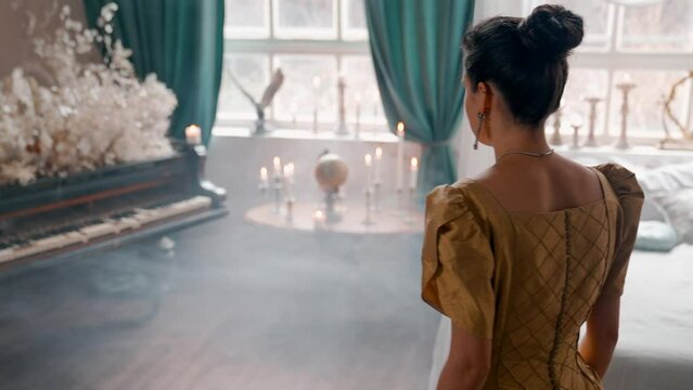 A Young Girl And Man Plays The Violin In A Beautiful Retro Room With Flowers And A Piano.