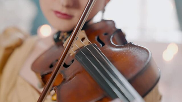 A Young Girl And Man Plays The Violin In A Beautiful Retro Room With Flowers And A Piano.
