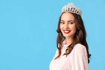 Beautiful young woman in stylish dress and tiara on blue background © Pixel-Shot