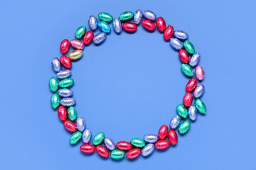 Frame made of tasty chocolate Easter eggs on color background