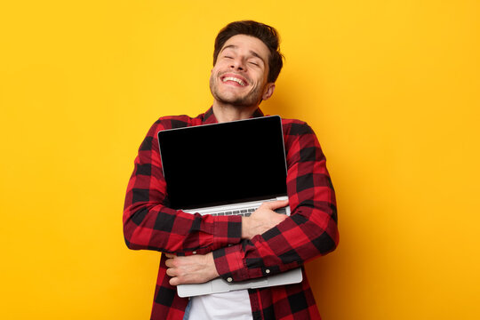 Technology Lover. Excited man hugging laptop at studio