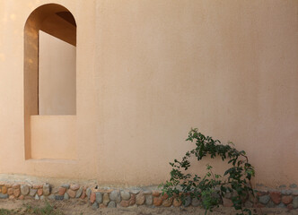 An arch window in the wall of the arabic building. Light shadows on the wall.