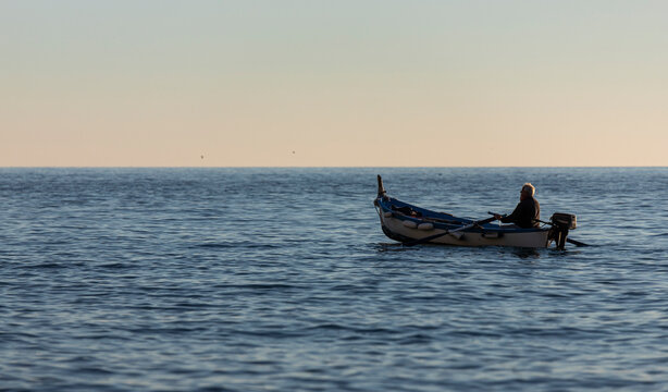 View of a fisherman sailing along the coast near Vernazza with a sailboat, Cinque Terre, Liguria, Italy.
