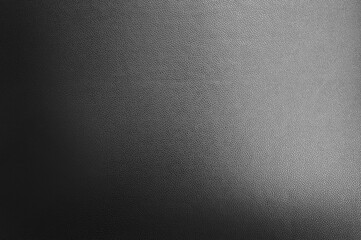 luxury black leather texture background showing grain and a shaft of light across. gradient black artificial leatherette texture use as background, close up view, with blank space for design.