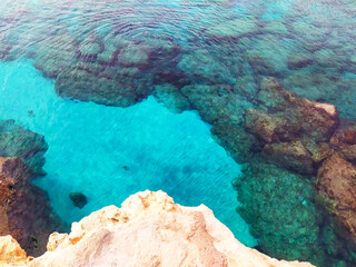 Rocky seabed with white sand and clear blue water. Lagre stones in the water, top view.