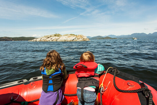 Two young kids look over the bow of a rubber raft in big bay