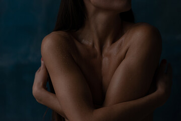 Close up woman in water drops  embracing herself by hands